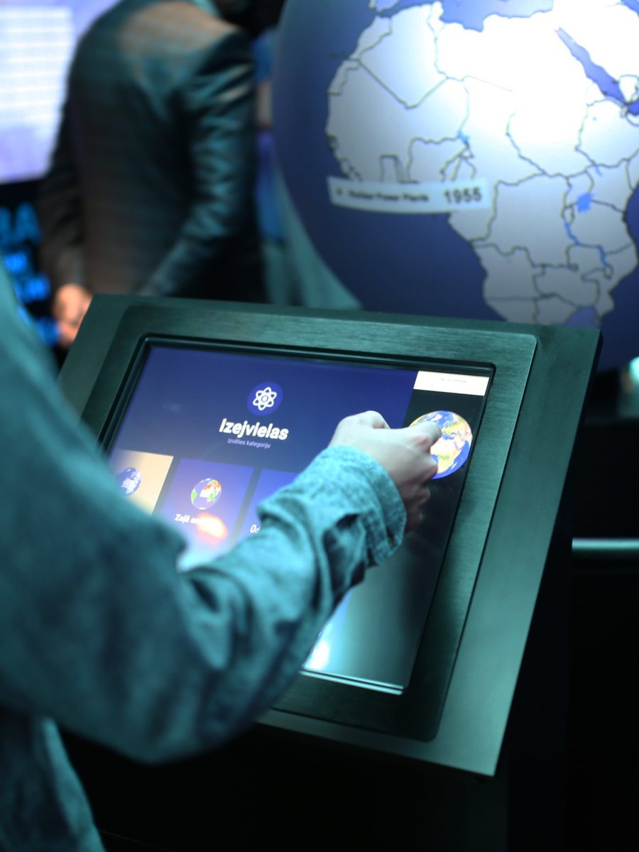 A visitor choosing a category on the touchscreen next to the globe